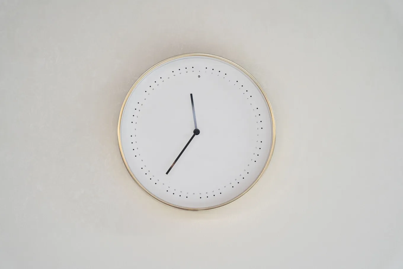 A minimalist white wall clock on a pale wall